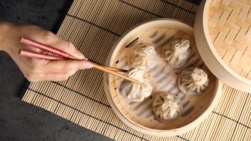 man using chopsticks to eat dumplings at a restaurant in Philadelphia