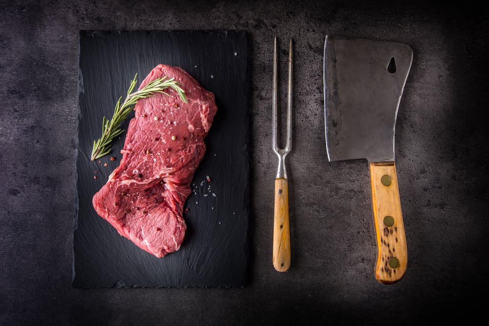 Beef raw rump steak with salt pepper rosemary butcher and fork.