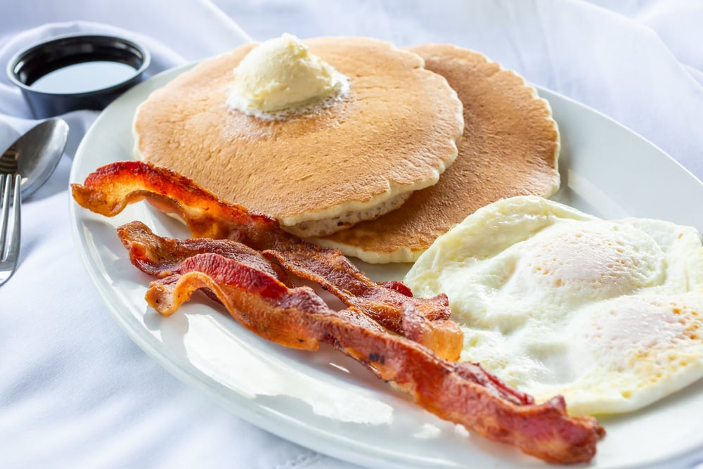 pancake breakfast plate featuring over easy eggs and strips of bacon in a Rochester restaurant