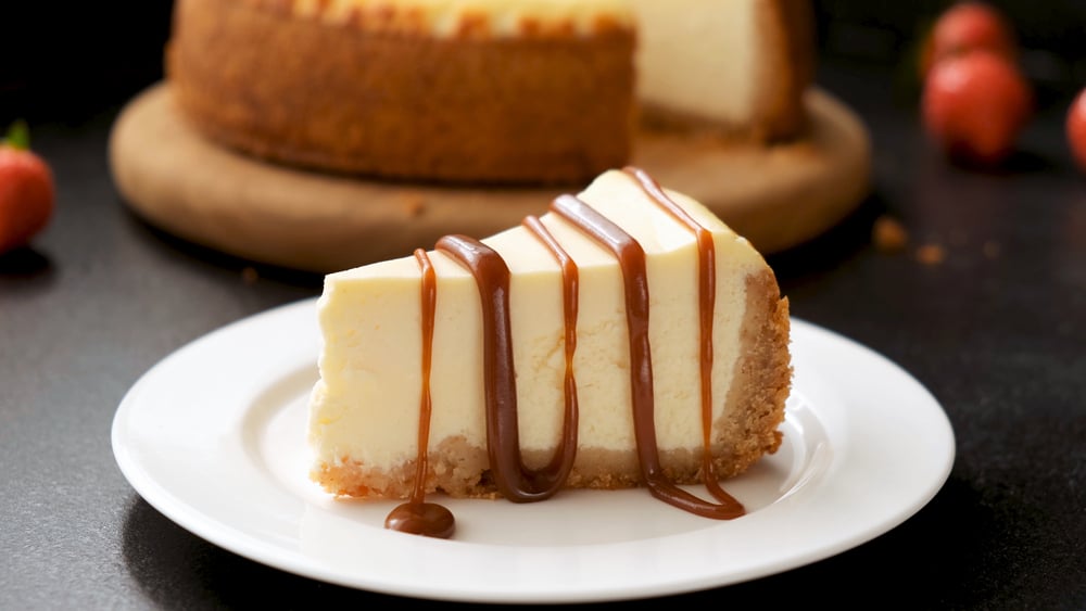 Cheesecake with caramel sauce on black background