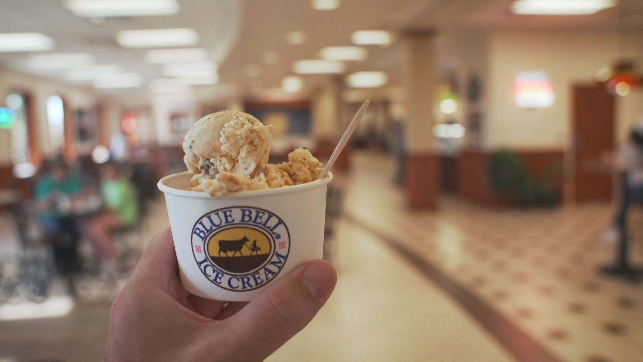 Hand holding ice cream scoop in a cup at Blue Bell