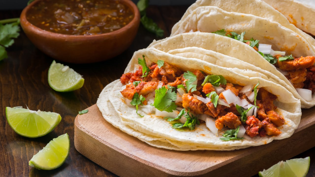 Authentic Mexican tacos on wooden surface with lime and salsa