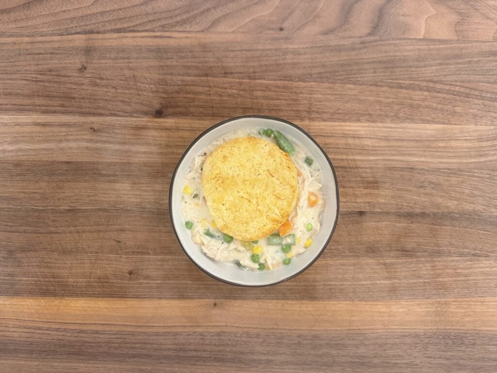 Overhead view of a bowl of chicken pot pie with a biscuit