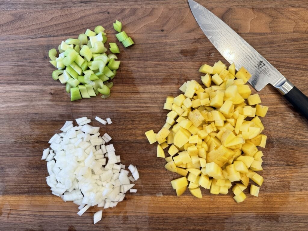 Diced Yukon gold potatoes, onion and celery on a cutting board