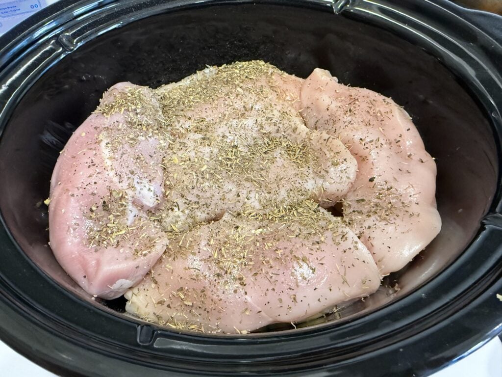 Chicken breasts seasoned with poultry seasoning and thyme on top of the vegetables